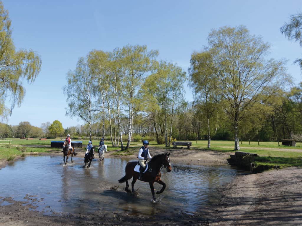 A group riding through a water jump