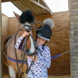 Girl bridling a pony