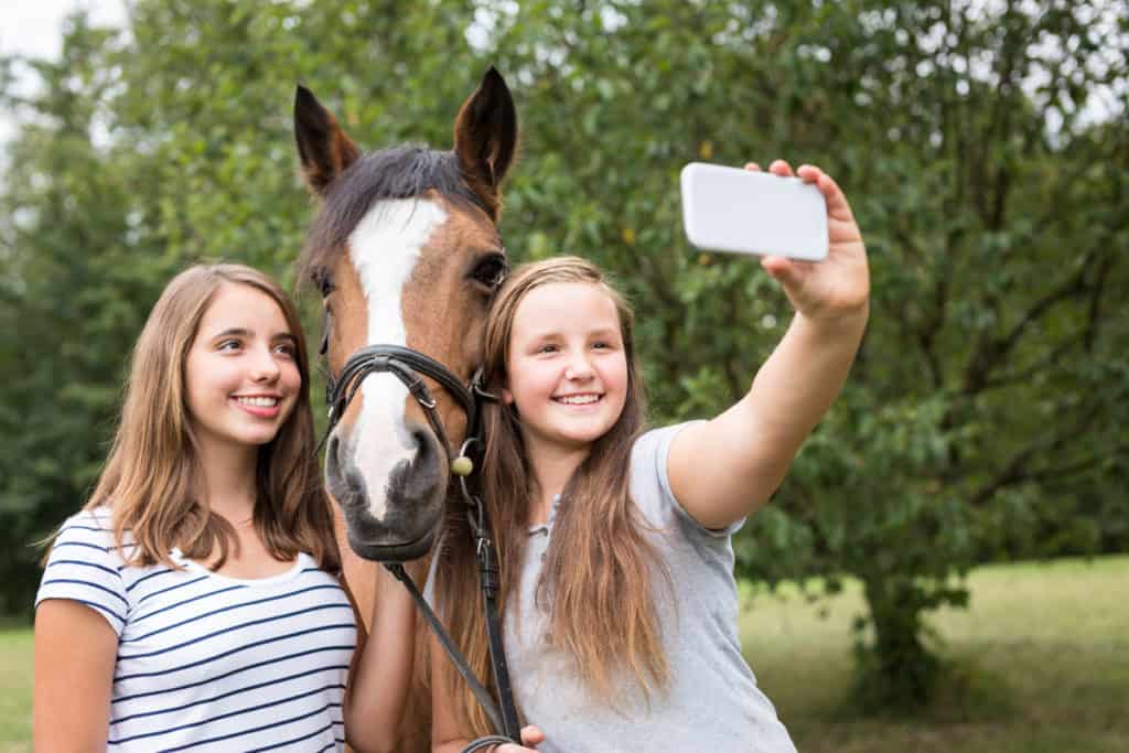 Girls taking selfie with pony